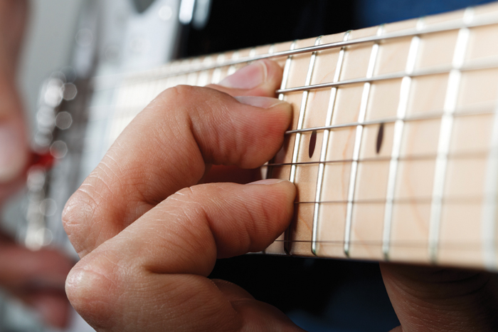 手的男人弹奏电吉他与红色挑的特写